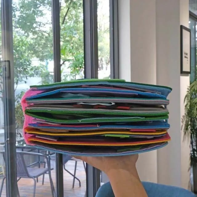 A hand holding the Montessori Story Book colorful educational toy and showing the number of pages it has. 